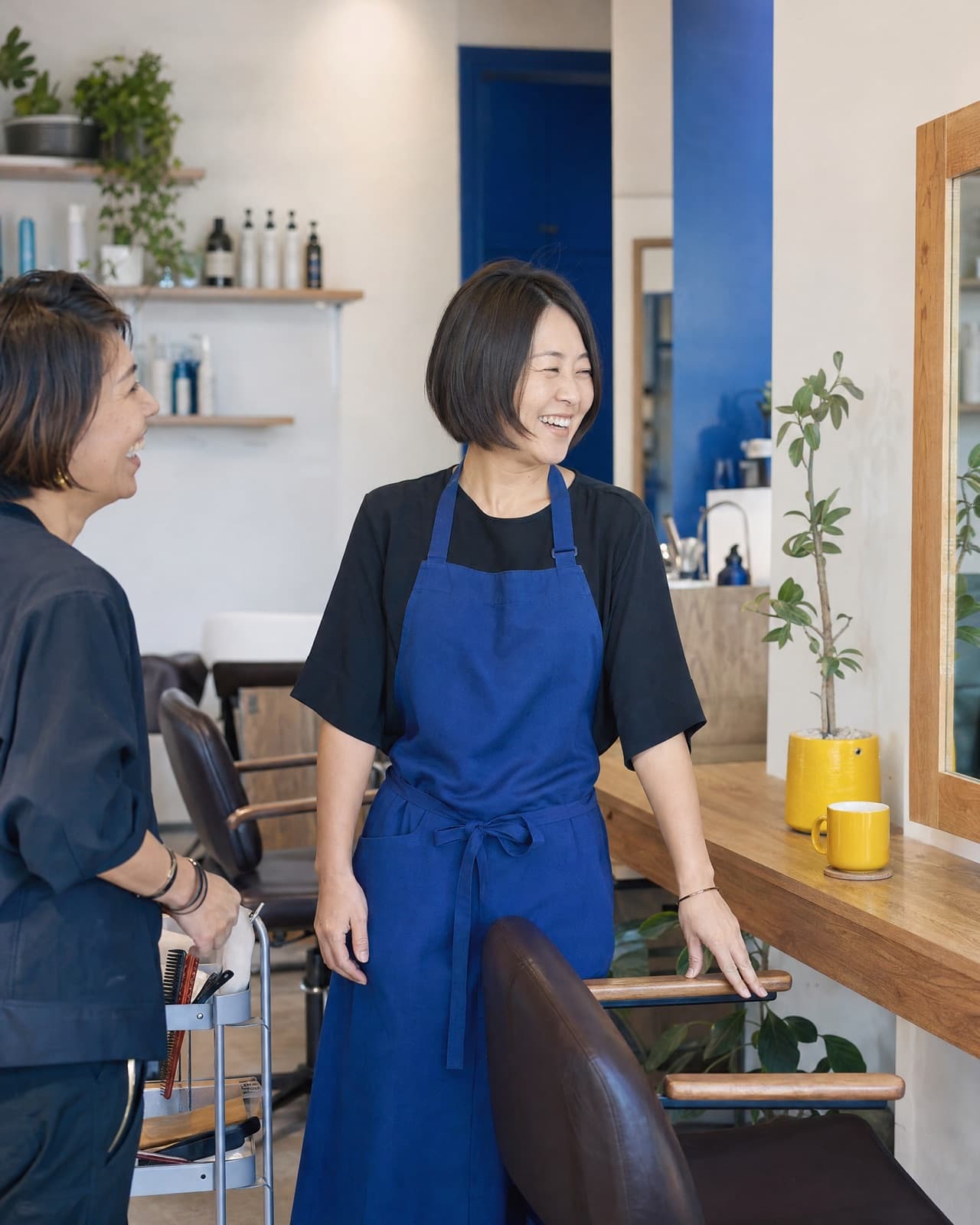 A salon owner laughing with a client in her shop
